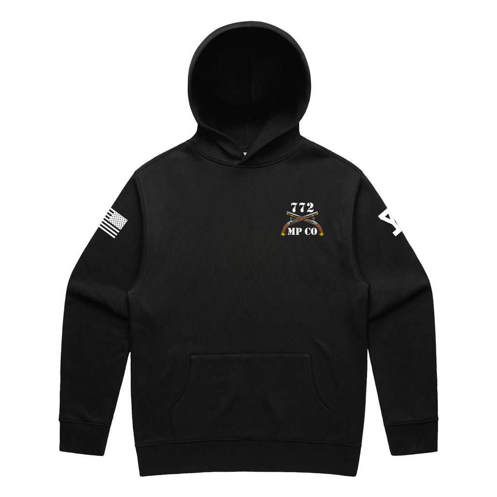 Front view of a black pullover hoodie for the 772nd Military Police Company. The left chest features a white graphic with the number '772' above a blue infantry disc and crossed flintlock pistols, with 'MP CO' written at the bottom. A white American flag patch is displayed on the right sleeve