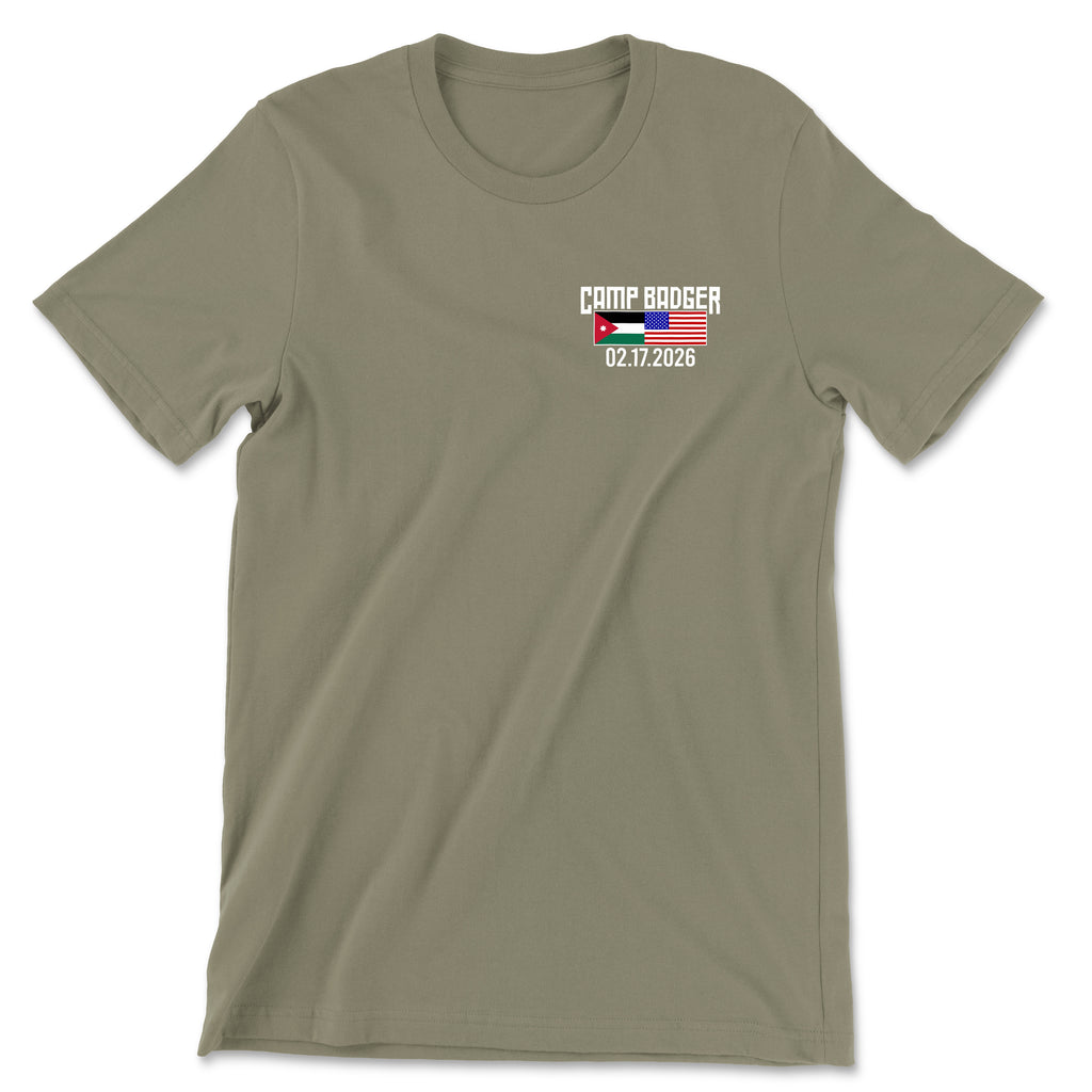 Front view of a coyote brown t-shirt for the Camp Badger Lunar New Year 5K. The left chest features a small graphic with the text 'CAMP BADGER' above the date '02.17.2026.' The design includes the national flags of Jordan and the United States side-by-side.