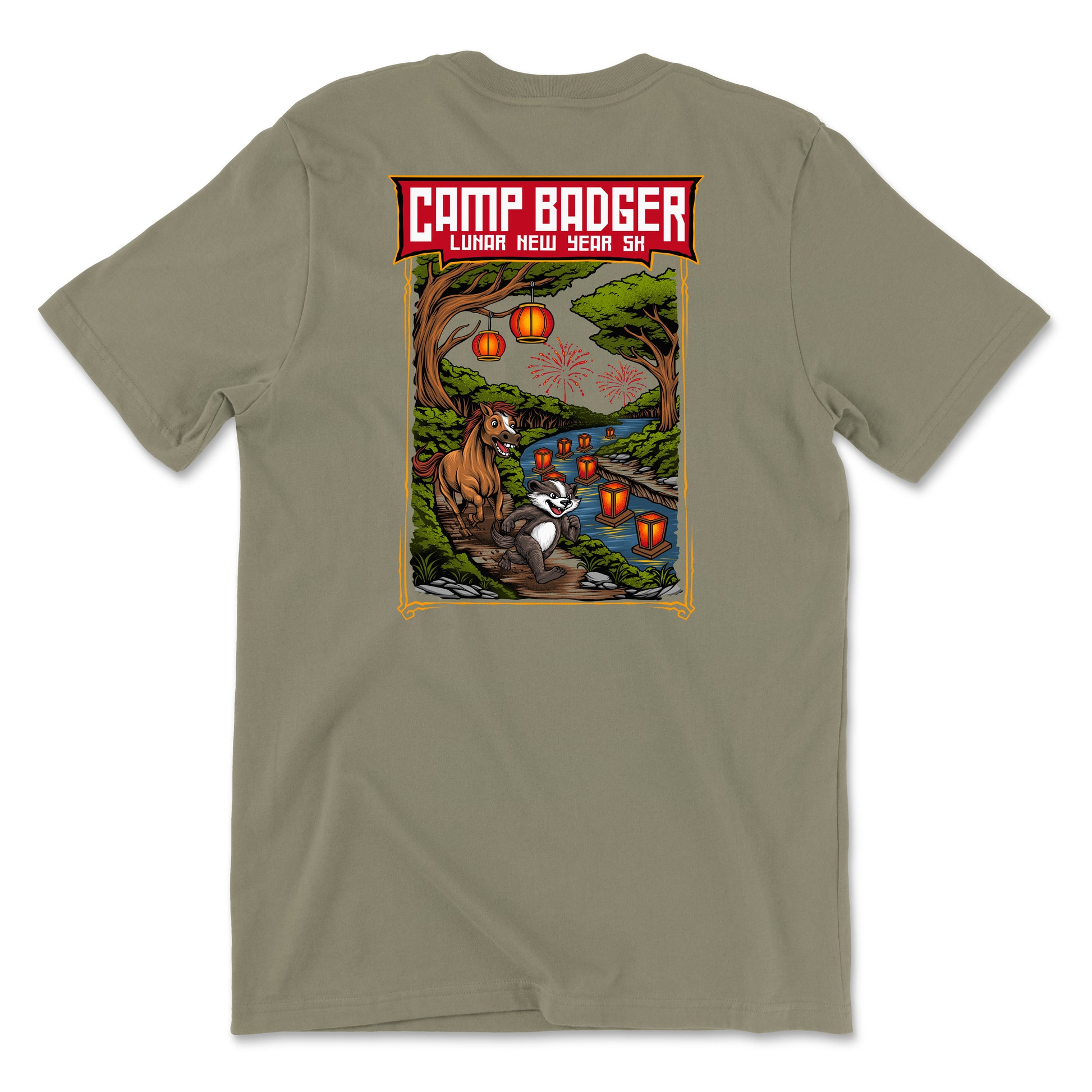Back view of a coyote brown t-shirt for the Camp Badger Lunar New Year 5K. The large rectangular graphic features a festive night scene with a badger and a horse standing by a river lit by glowing red lanterns. The text 'CAMP BADGER' is displayed in bold at the top, followed by 'LUNAR NEW YEAR 5K' against a background of a forest, a bridge, and fireworks in the sky.